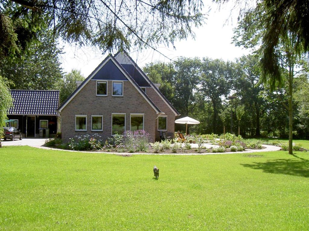a dog standing in the grass in front of a house at Rural holiday home with terrace in Zuidwolde