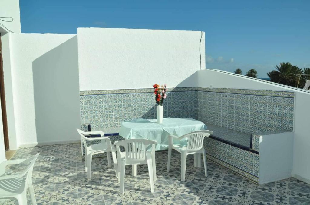 una mesa y sillas blancas y un jarrón en el balcón en City Apartment sur le port de Mahdia Free Wifi, en Mahdia