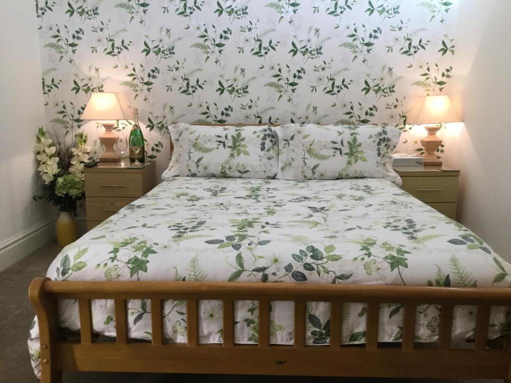 1 dormitorio con 1 cama y papel pintado con motivos florales en Pilkingtons Guest House Accrington, en Accrington