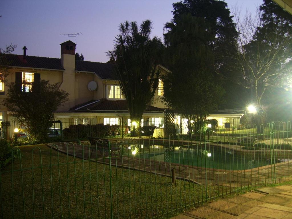 a house with a fence around a swimming pool at night at Nutmeg Guest House in Howick