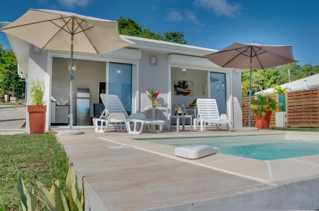 une maison avec une piscine entourée de chaises et de parasols dans l'établissement Les Terrasses du Cap, au Marin