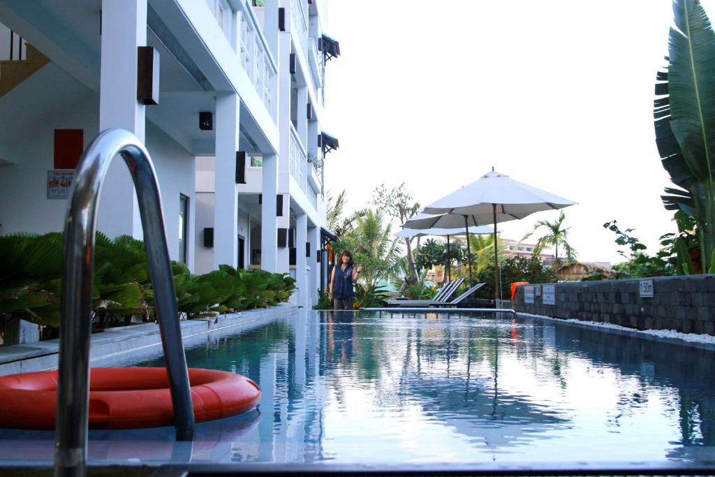 a swimming pool at a hotel with a person standing next to a building at Hoi An Corn Riverside Villa in Hoi An