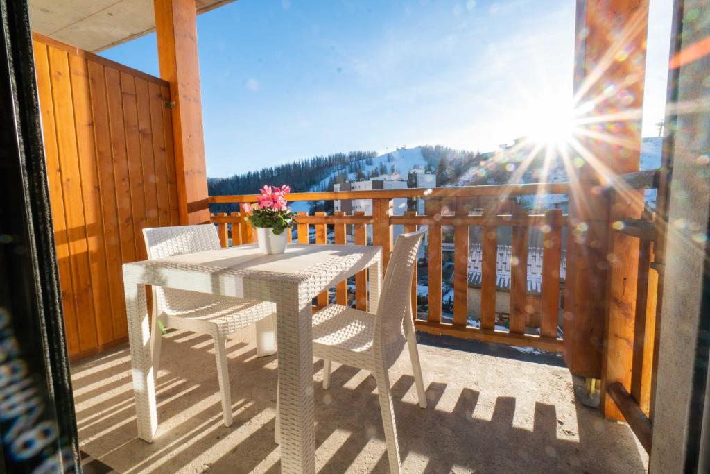 a white table and chairs on a balcony with the sun at Appartement Valberg in Valberg