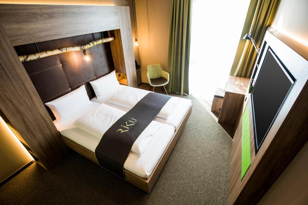 a bedroom with a large bed with a wooden headboard at RiKu HOTEL Ulm in Ulm