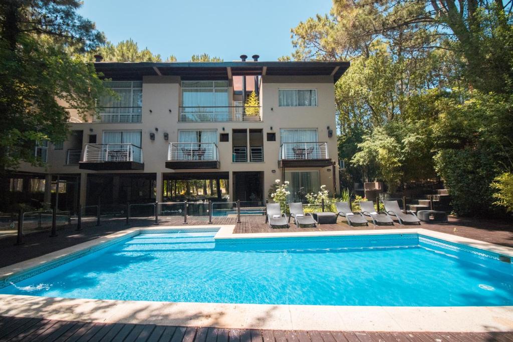 a house with a swimming pool in front of a building at Sonidos Del Bosque in Mar de las Pampas