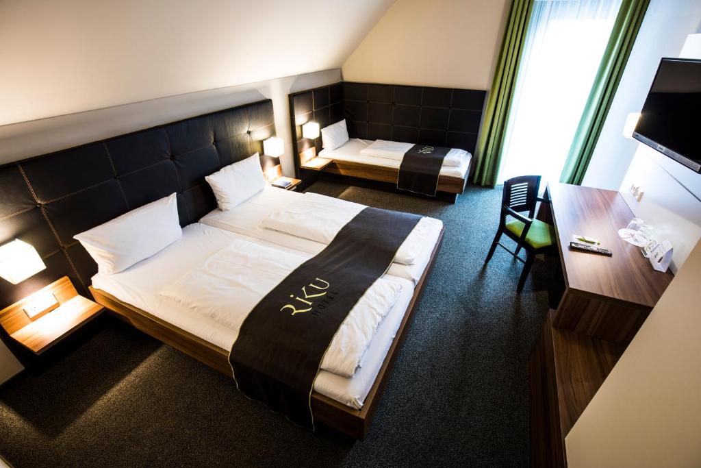 a hotel room with two beds and a desk at RiKu HOTEL Weißenhorn in Weißenhorn