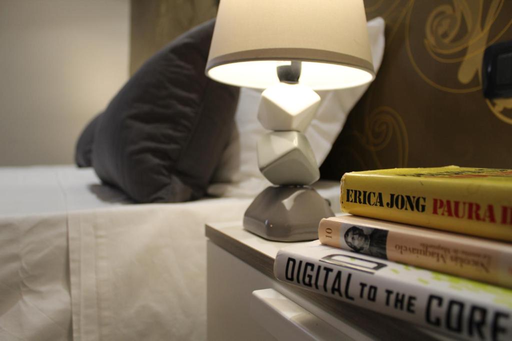 a lamp sitting on top of a stack of books next to a bed at Blu Mare - Milazzo in Milazzo