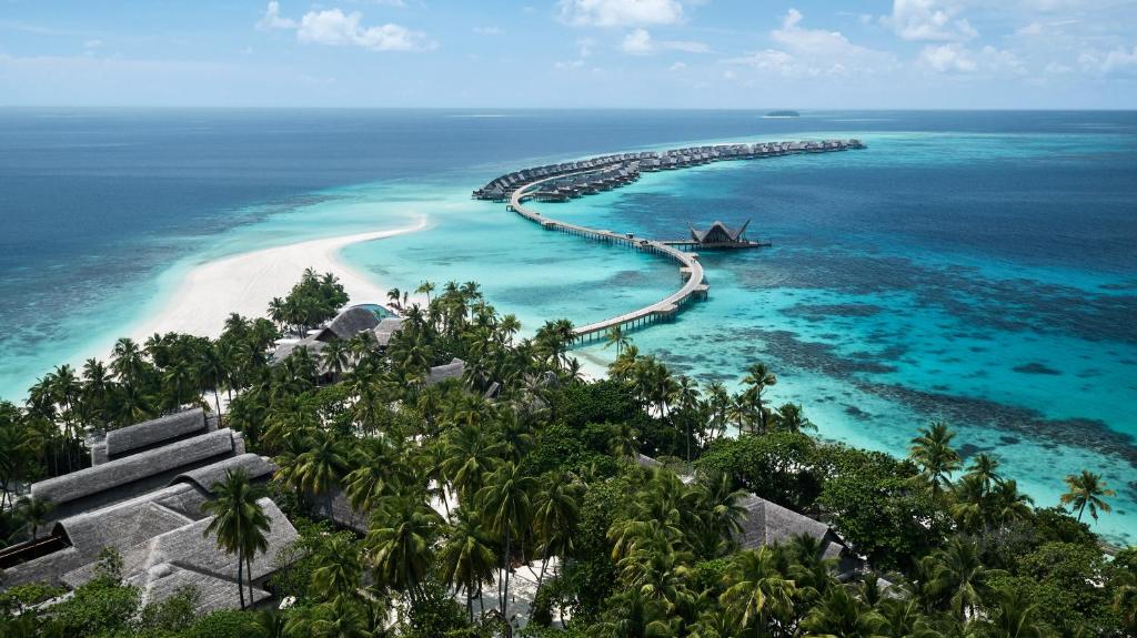 eine Insel im Ozean mit einem Boot im Wasser in der Unterkunft JOALI Maldives in Raa Atoll