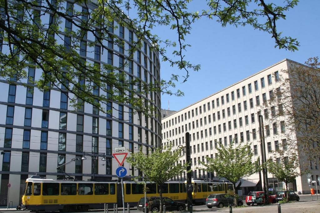 un autobús amarillo en una calle de la ciudad con edificios en Holiday at Alexanderplatz Apartments, en Berlín