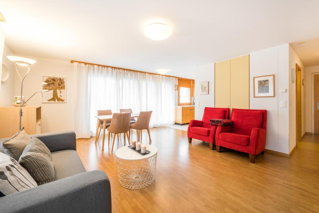 sala de estar con sillas rojas y mesa en LAAX Homes - Val Mulin 8,2 - Scarpazza, en Laax