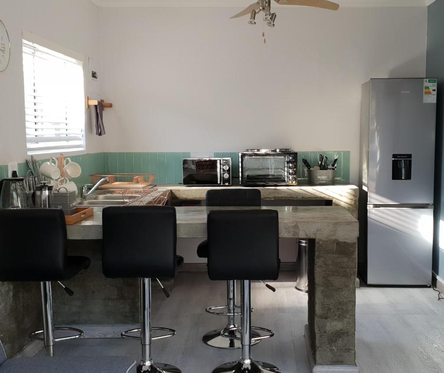 a kitchen with a table with chairs and a refrigerator at Emmaus Apartment in Bloemfontein