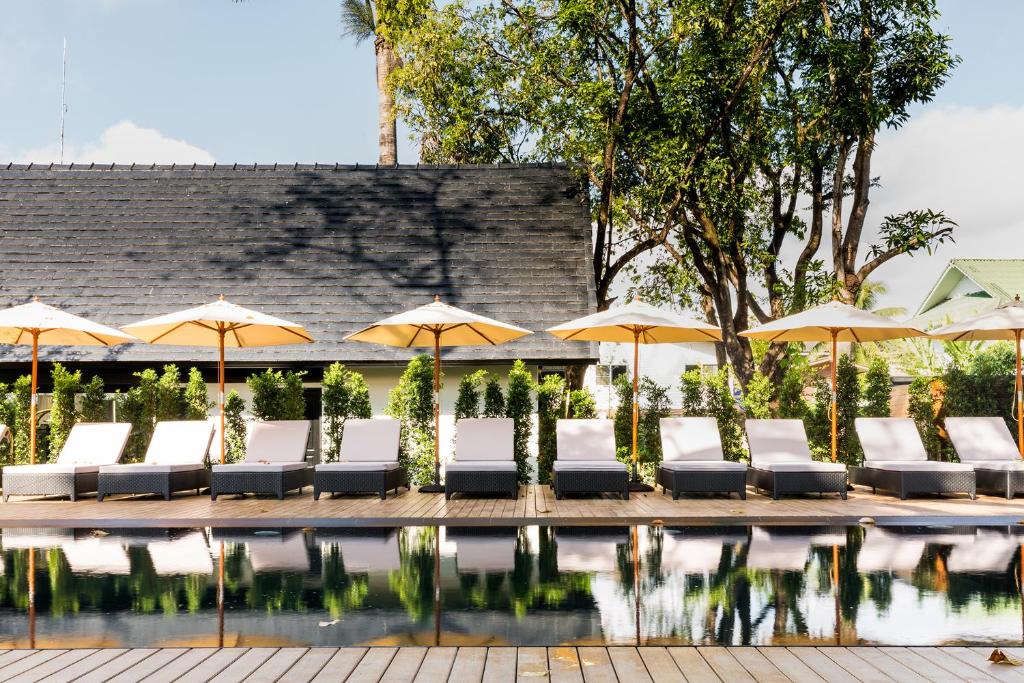 a group of chairs and umbrellas next to a pool at MORA Boutique Hotel - SHA Extra Plus in Chiang Rai