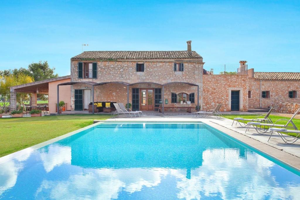 a villa with a swimming pool in front of a house at Finca Maria in Manacor