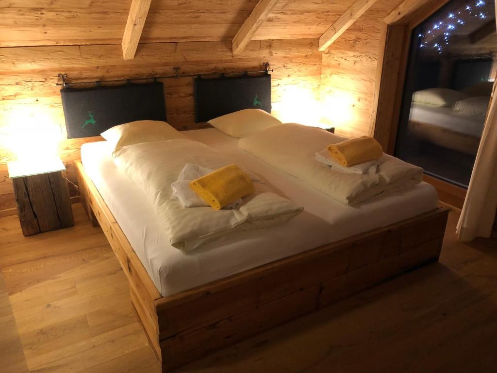a bedroom with a large bed with white sheets and yellow pillows at Lachtalchalet in Oberwölz Stadt