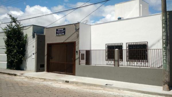 un edificio blanco con una puerta marrón en una calle en Casa no centro com 4 quartos e ar condicionado en São João Batista do Glória