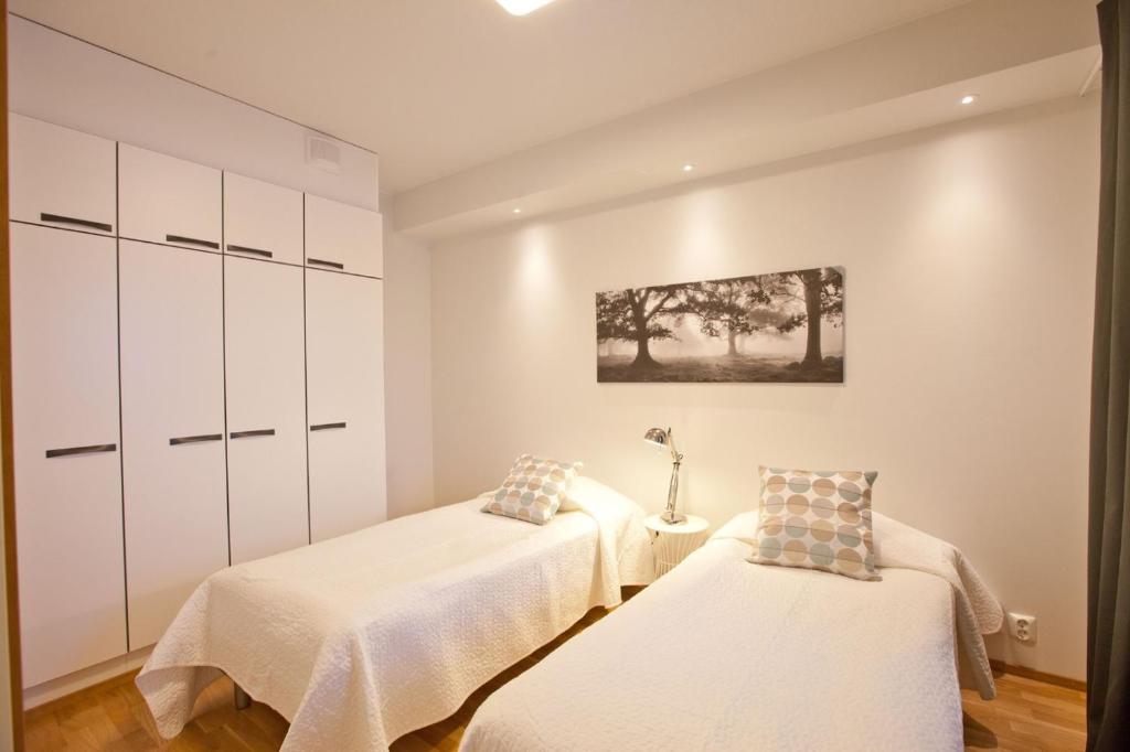 2 camas en una habitación con armarios blancos en Kansankatu Apartments, en Rovaniemi