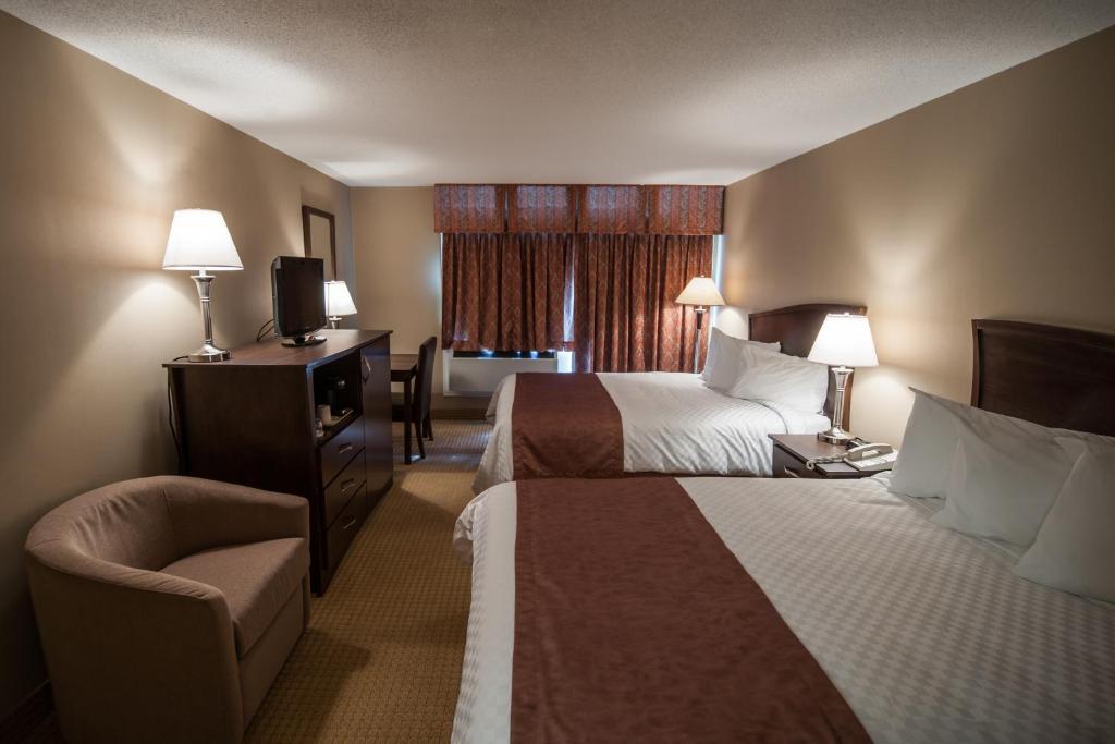 une chambre d'hôtel avec deux lits et une chaise dans l'établissement Deer Lake Motel, à Deer Lake