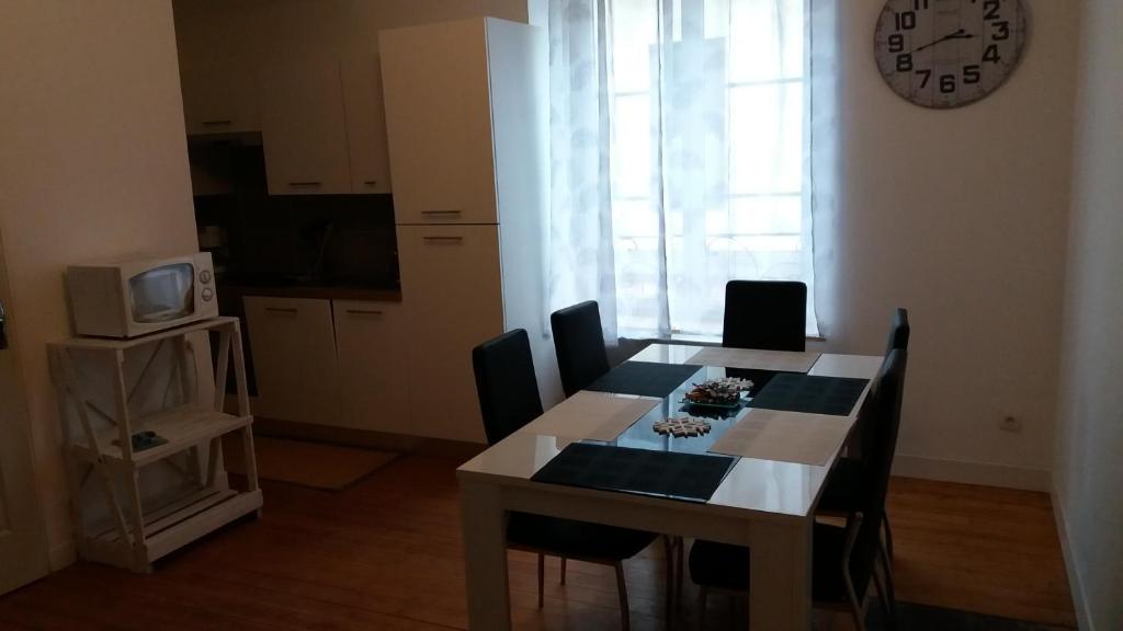 a dining room table with chairs and a clock on the wall at Appartement Taïko in La Flèche