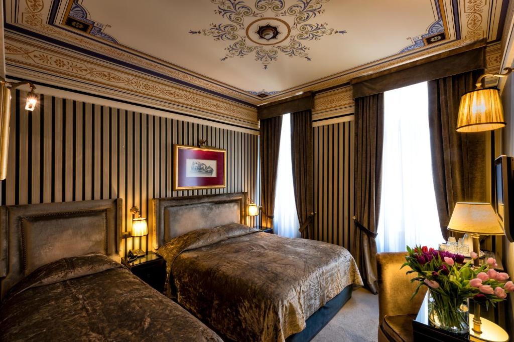 a bedroom with two beds and flowers in a room at Maison Grecque Hotel Extraordinaire in Patra