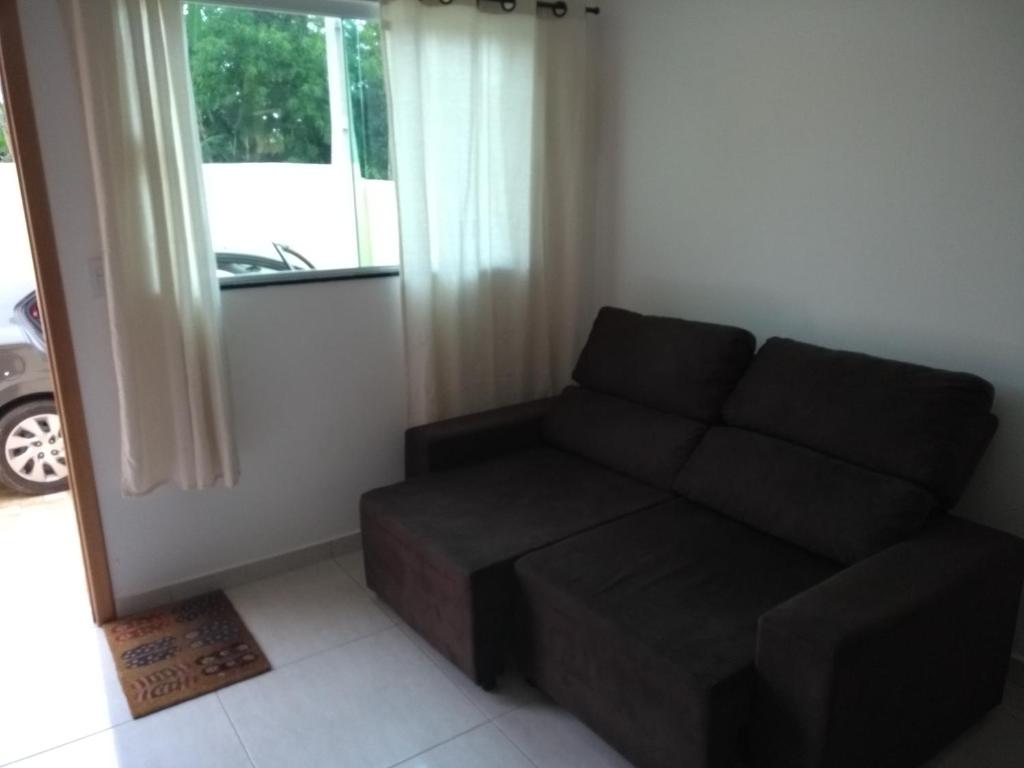 a living room with a black couch and a window at Casa de praia litoral norte SP in Caraguatatuba