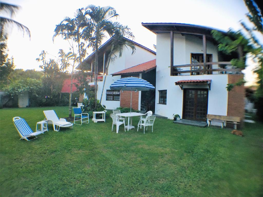 a yard with chairs and a table with an umbrella at Casanapraia Bertioga in Bertioga