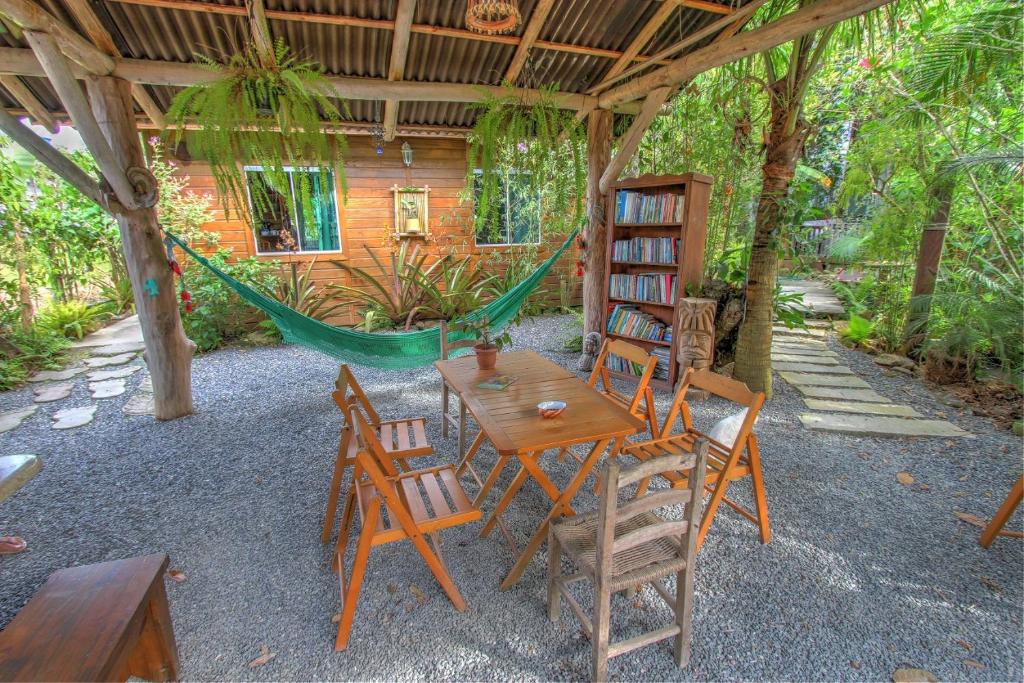 a patio with a table and chairs and a hammock at Vila Equilíbrio Natural in Bombinhas