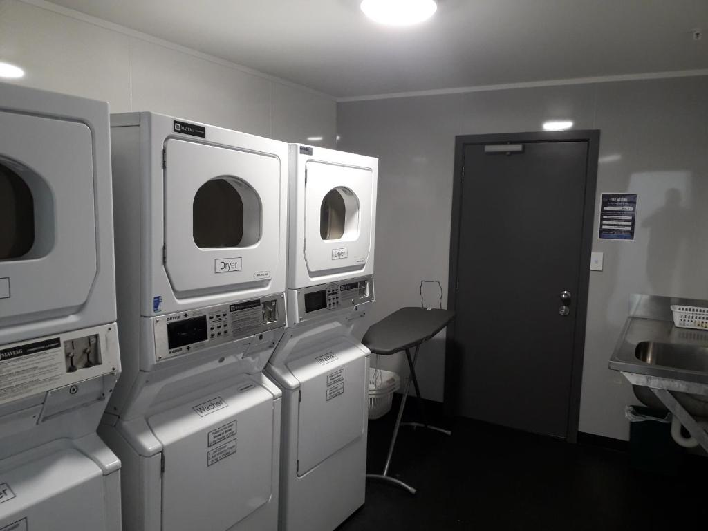 a laundry room with three microwaves and a door at YHA Nelson in Nelson