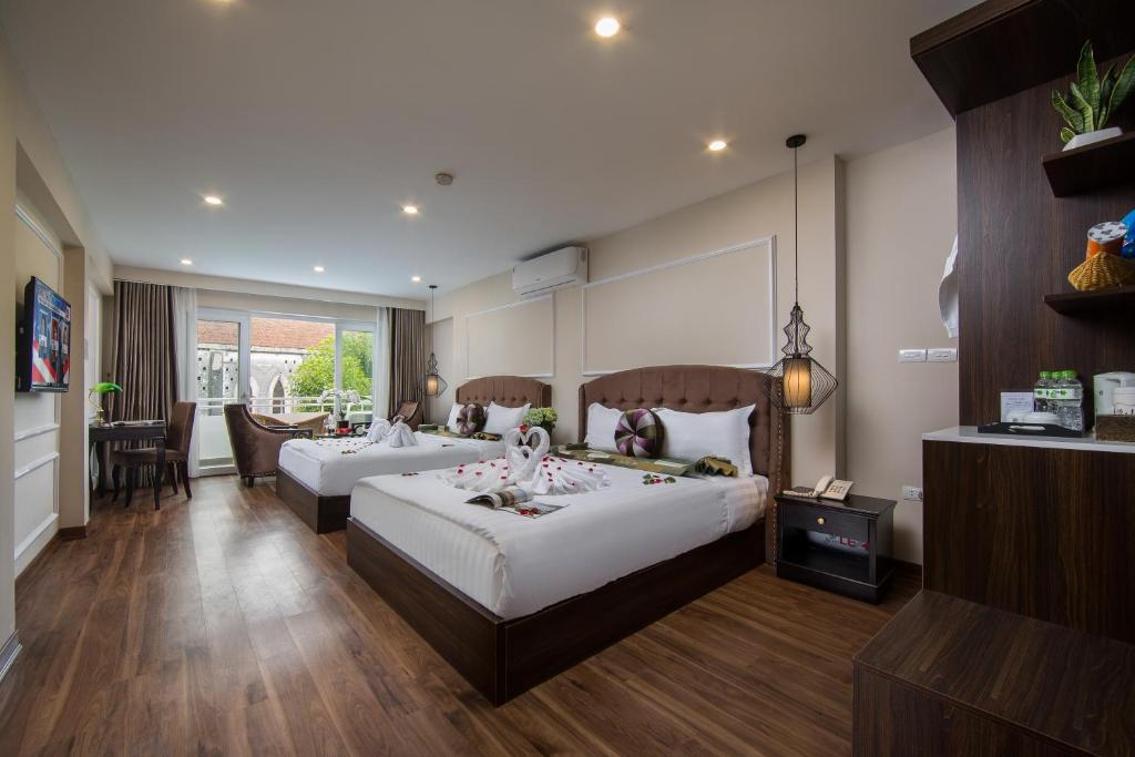 a hotel room with two beds and a dining area at Splendid Pearlight Hanoi in Hanoi