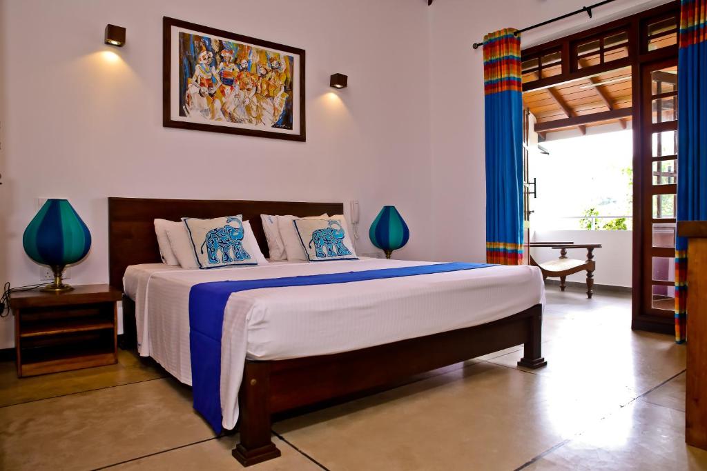 a bedroom with a large bed with blue curtains at Blue Elephant Boutique Hotel in Negombo