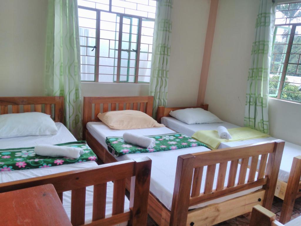 um quarto com três camas e janelas em Savta Homestay em Banaue