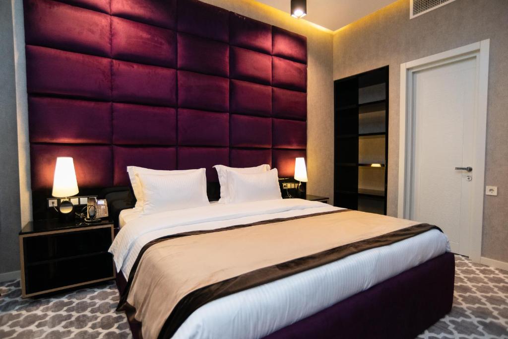 a bedroom with a large bed with a red headboard at Gallery Art Hotel in Tbilisi City