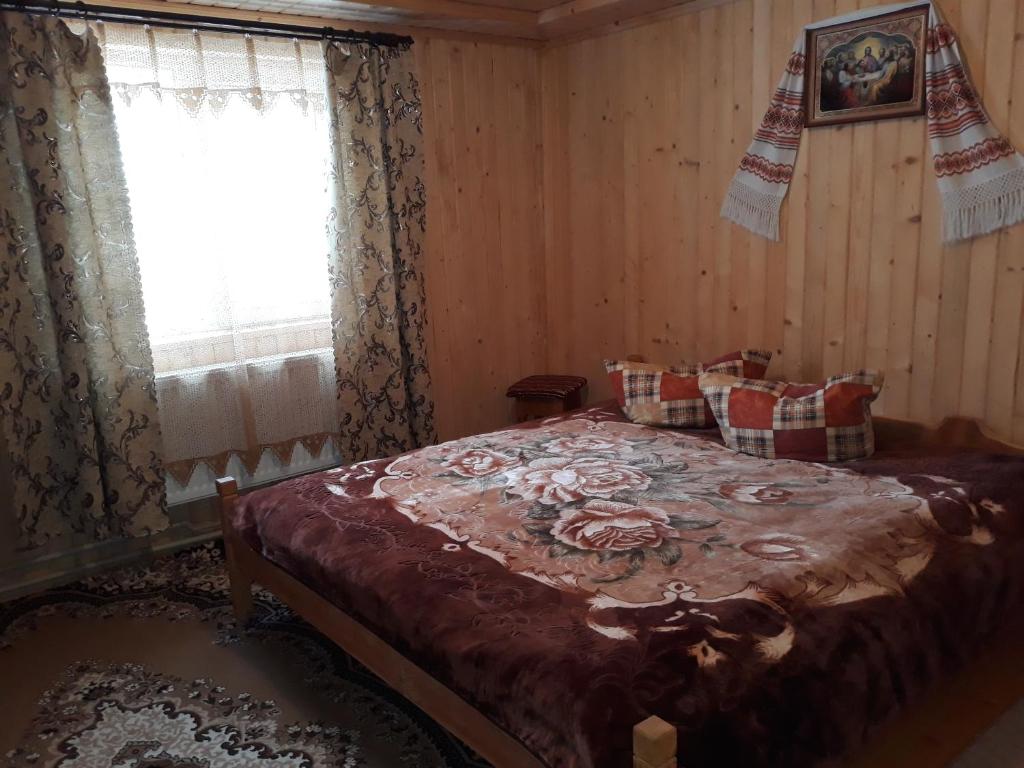 - une chambre avec un grand lit et une fenêtre dans l'établissement Яблуневий сад, à Yablunytsya