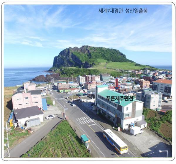 a city with a mountain in the background and a street at Preun Jeju Pension in Seogwipo