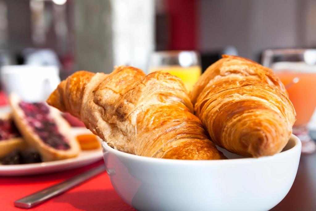a bowl of croissants and bread on a table at Hôtel Le Nautic in Arcachon