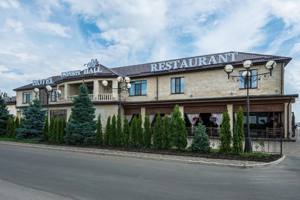 un edificio de restaurantes con un cartel en la parte delantera en Sweet Hall Hotel, en Krasnodar