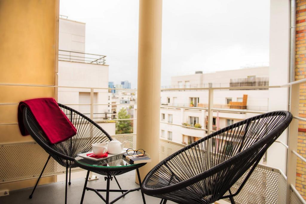 einen Balkon mit 2 Stühlen und einem Tisch mit Tassen in der Unterkunft Mercure Paris Pont de Levallois Neuilly in Levallois-Perret