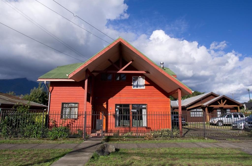 czerwony dom z zielonym dachem w obiekcie Hostal Emalafquen w mieście Pucón