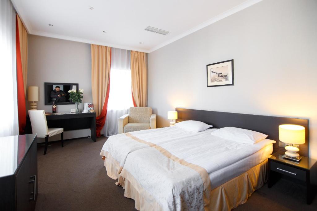 una camera d'albergo con un grande letto e una scrivania di Optima Kropivnytskiy Hotel a Kropyvnyc'kyj