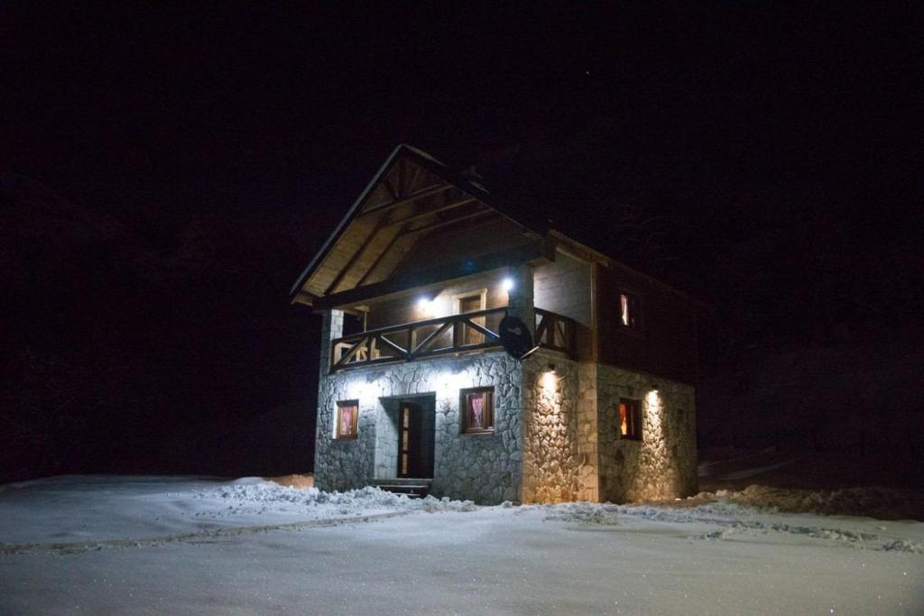 - un bâtiment en pierre avec des lumières allumées la nuit dans l'établissement BB Etno House, à Kolašin