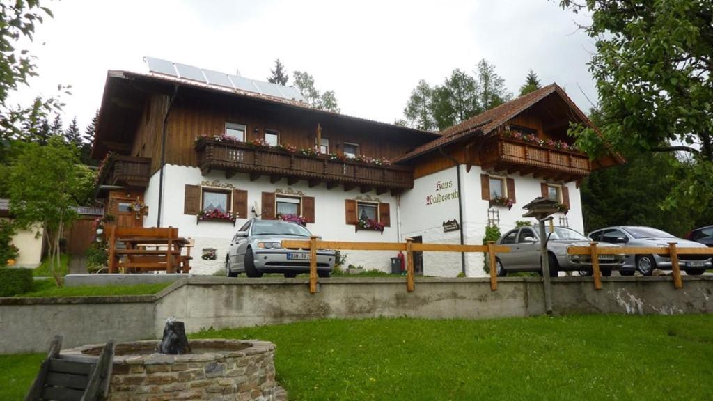 une maison avec des voitures garées devant elle dans l'établissement Pension Haus Waldesruh, à Lohberg