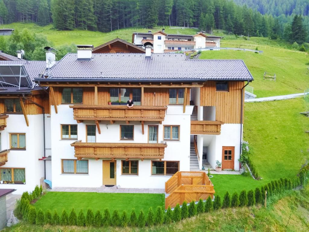 ein großes Haus mit Holzbalkonen und einem grünen Hof in der Unterkunft Ferienwohnung Plattner in Schmirn