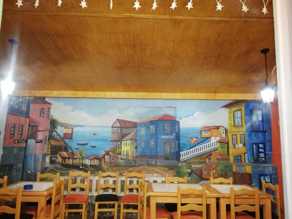 Un mural en la pared de un restaurante con mesas y sillas. en Hostal Vicmar, en Viña del Mar
