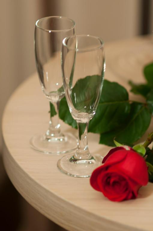 two wine glasses and a red rose on a shelf at Alma di Alghero Hotel in Alghero