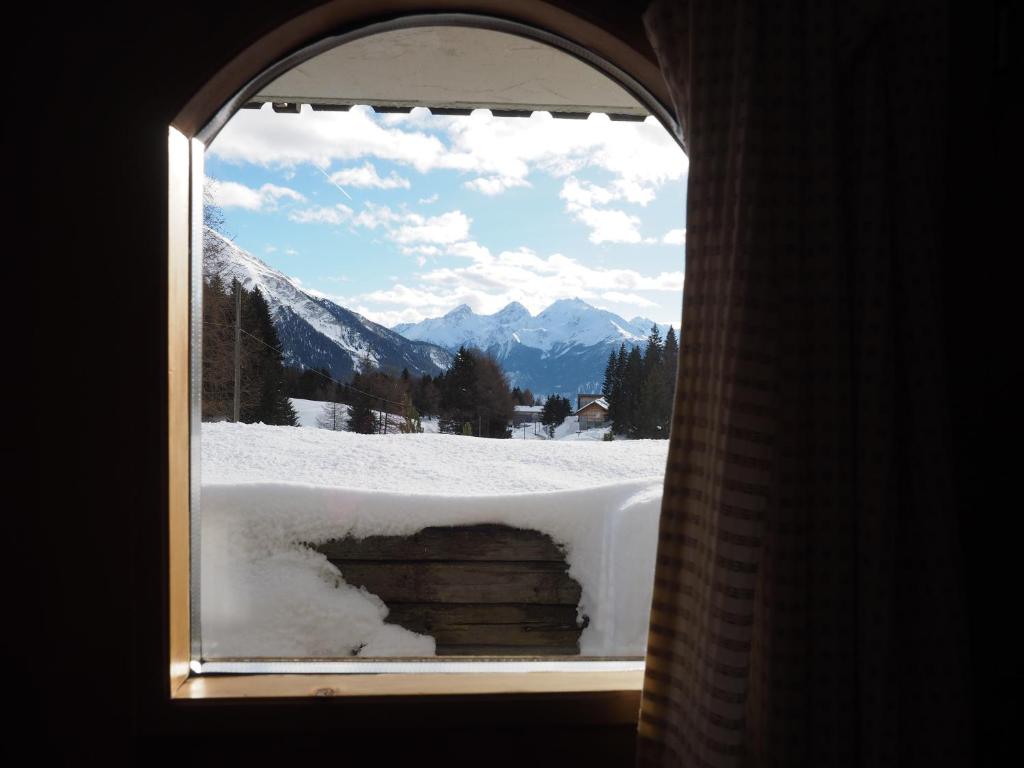una ventana con vistas a una montaña nevada en Tgantieni Sot - Apartment mit Herz, en Lenzerheide