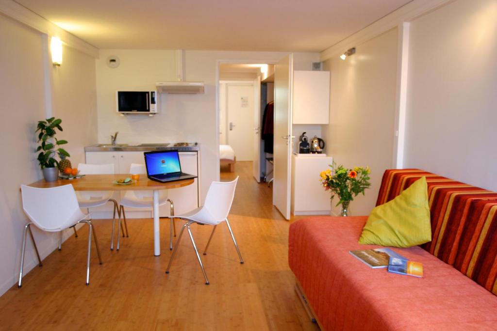 sala de estar con sofá y mesa con ordenador portátil en Hôtel Pierre Blanche en Châtillon-en-Michaille