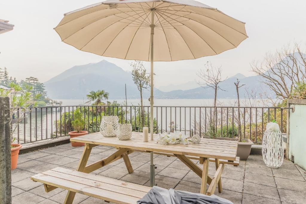 a wooden table with an umbrella on a patio at Casa Paola in Perledo