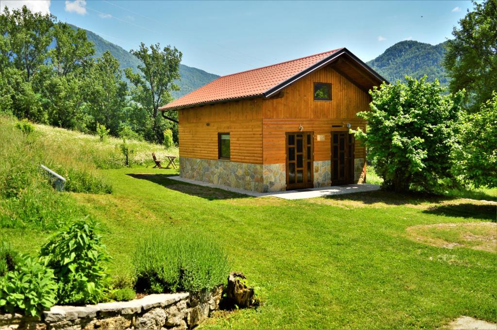 a wooden cabin in a field of grass with mountains at Sleeping with the bees Kozjak in Kobarid