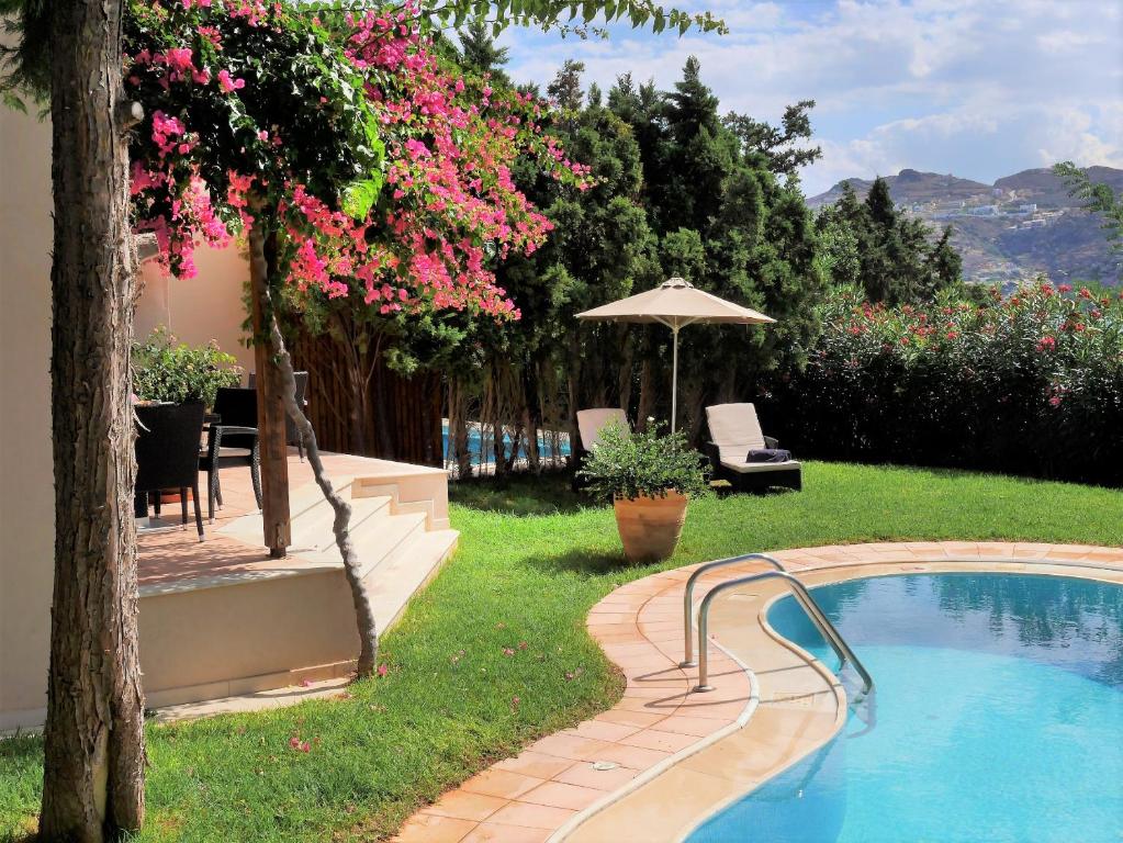 a swimming pool in a yard with pink flowers at Out Of The Blue Resort & Spa in Agia Pelagia