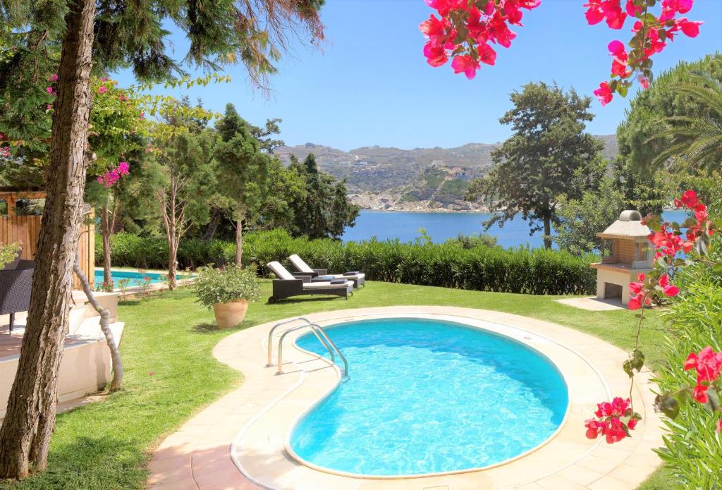 a swimming pool in a yard with a view of the water at Out Of The Blue Resort & Spa in Agia Pelagia