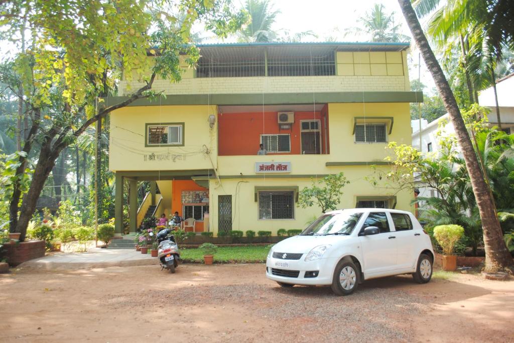 une voiture blanche garée devant un bâtiment dans l'établissement Hotel Anjali Lodge Malvan, à Malvan